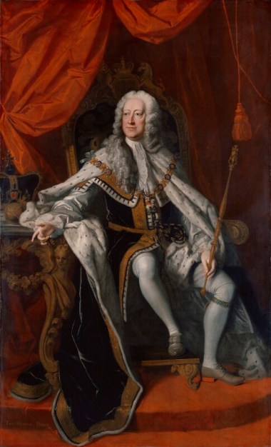 Portrait oil painting of King George II sat on a throne with a table to his right on which the crown sits. He is wearing white lace cravat and ruffles, blue ermine robes of state. white hose, and grey shoes. He has a long grey wig on. The backdrop is scarlet red drapes.
