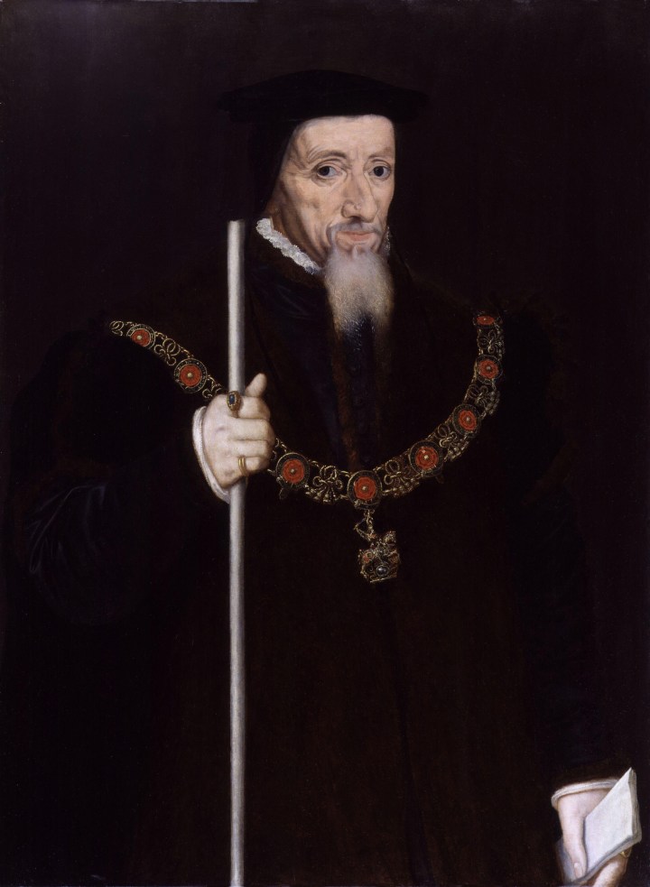 Elderly man with white beard, wearing a dark robe and the insignia of the order of the Garter, and holding a white staff