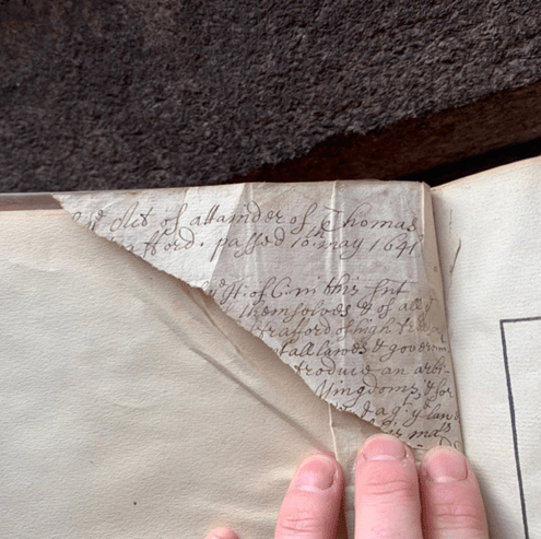 Image of a torn piece of paper from a copy of F. Poulton, Collection of Sundry Statues (1636). The paper shows scrawled handwriting, possibly by John Robartes, referending the trial of Thomas Wentworth, 1st earl of Strafford.